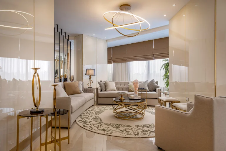 Luxury modern living room design by Aghbary Tex Egypt showcasing beige velvet sofas, gold metal coffee tables, a chic golden chandelier, and high-gloss marble flooring with a classic patterned rug